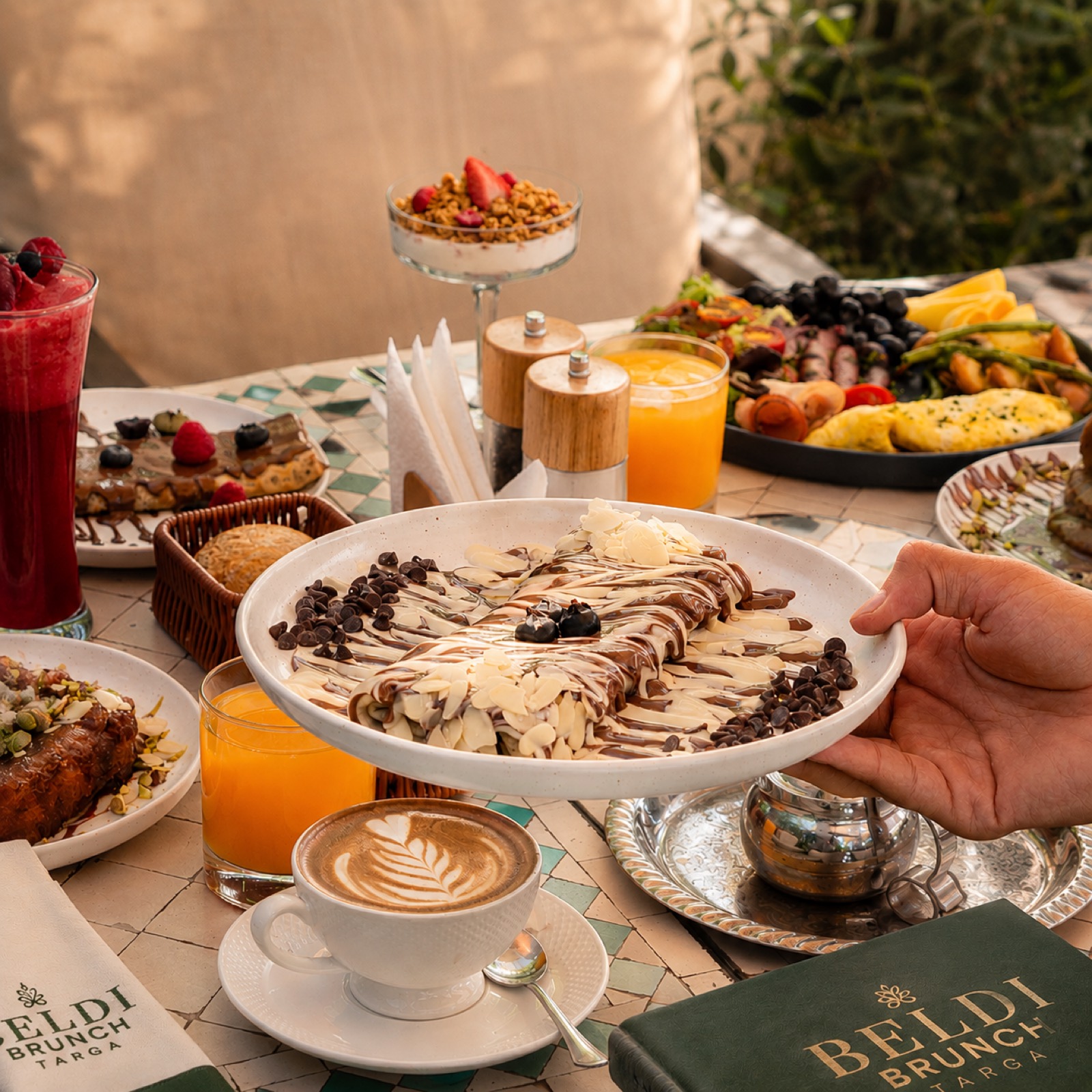 Table dressée : msemen, fruits, café latte et jus