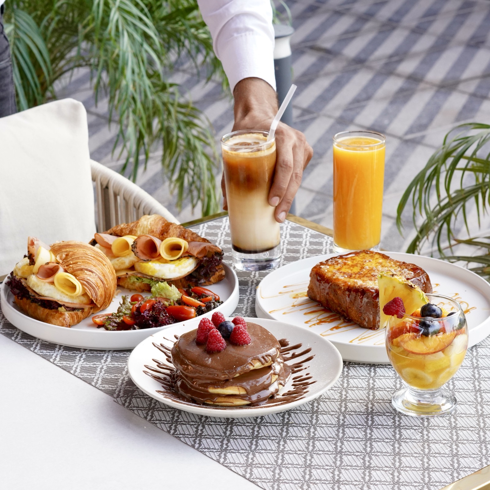 Brioche, pancakes et jus servis sur la terrasse